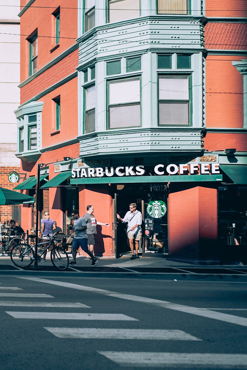 people walking in front of a starbucks coffee shop on a city street