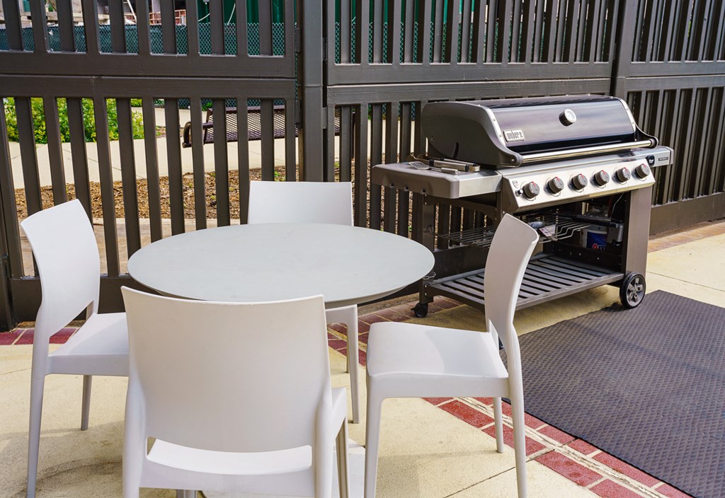 a patio with a grill and a table and chairs