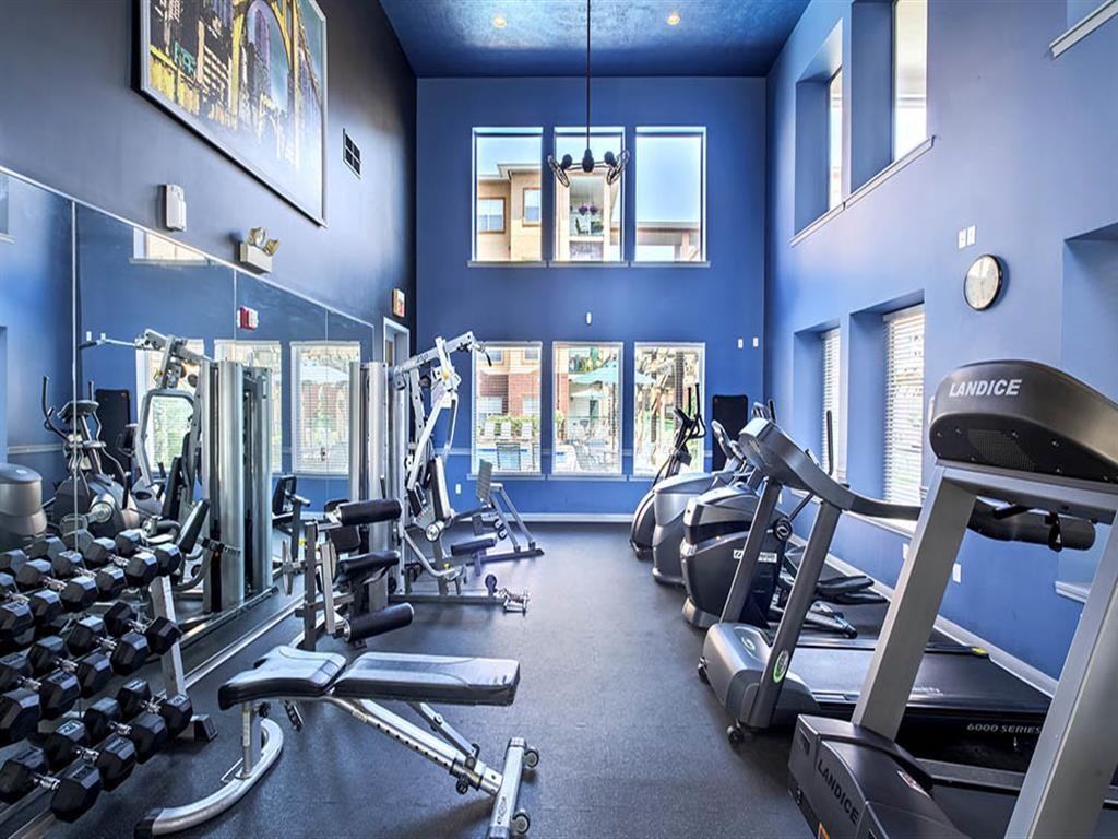 a gym with cardio equipment and windows in a building