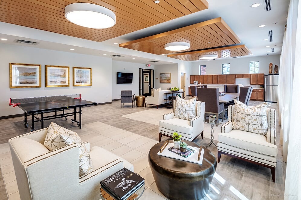 A spacious living room with a wooden ceiling and furnished with a sofa, armchairs, and a coffee table.