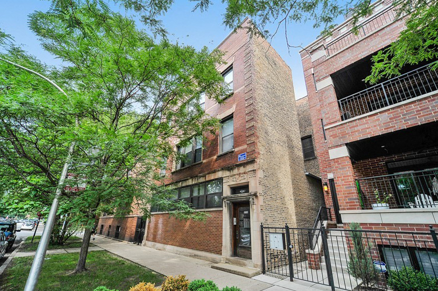 a brick building with a sidewalk and trees in front of it