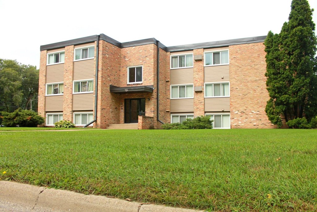 an apartment building with a green lawn in front of it