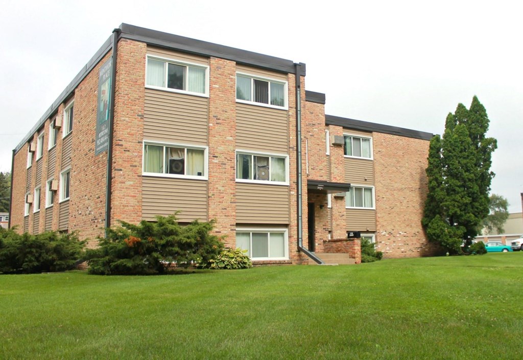 an apartment building with a green lawn in front of it