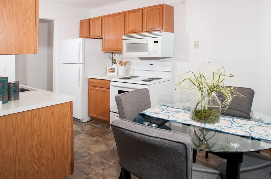 a kitchen with white appliances and a table with chairs