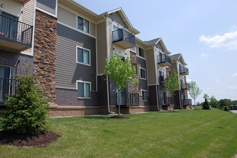 an exterior view of an apartment building with grass and trees