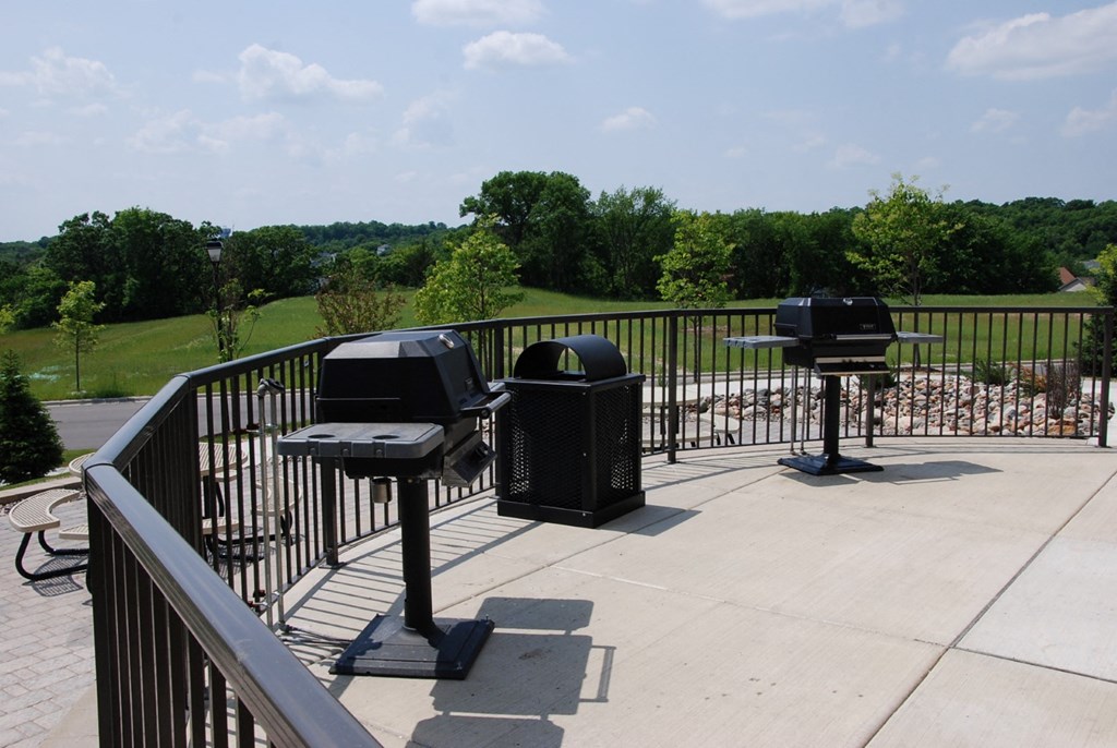 a patio with two grill pits and tables on a roof