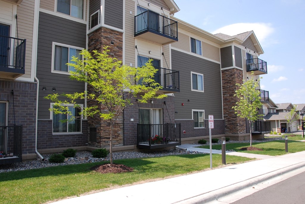 an exterior view of an apartment building with green grass and trees