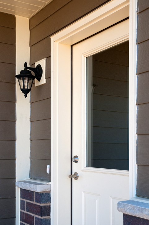a white door with a window and a light on the side of a house