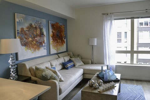 A living room with a white couch and a coffee table with blue vases on it.