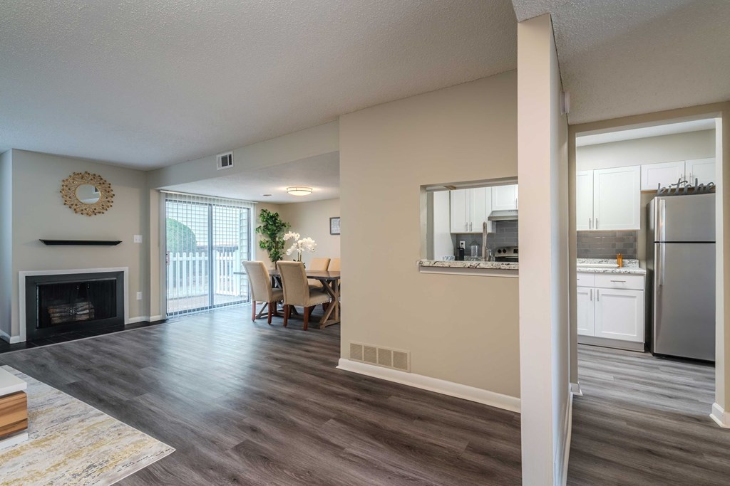 a living room with a fireplace and a kitchen with a table and chairs