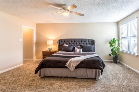 the master bedroom has a large bed and a ceiling fan
