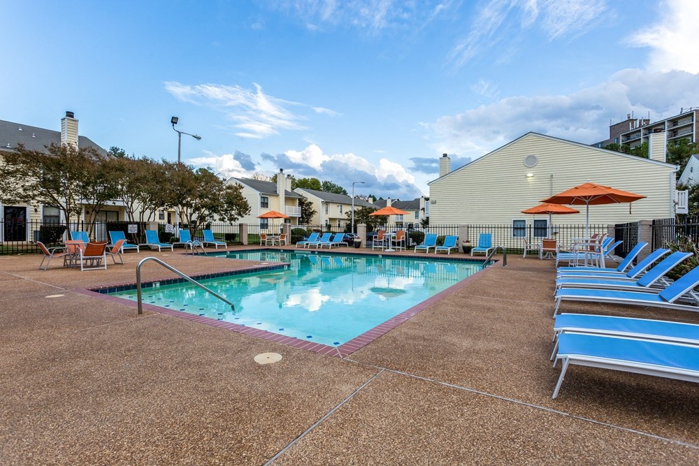 our resort style swimming pool is surrounded by lounge chairs and umbrellas