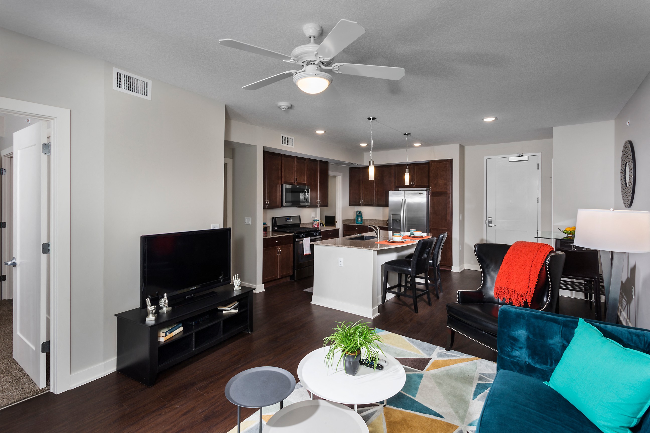 a living room area with tv and kitchen in background