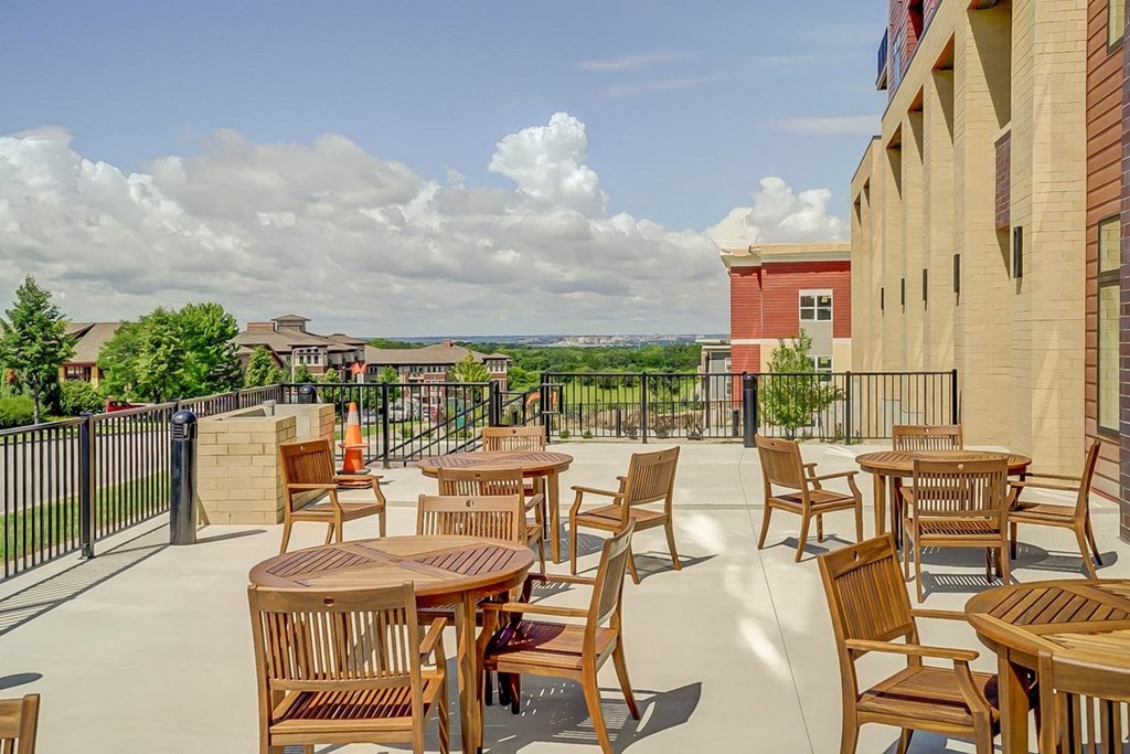 a patio with tables and chairs on the balcony of a building