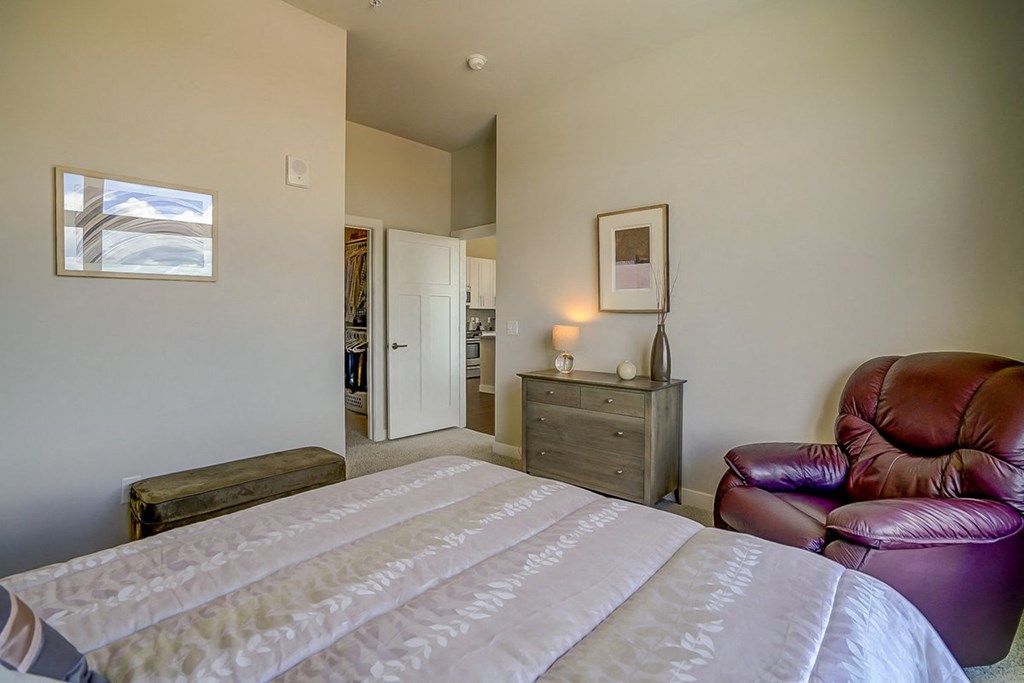 a bedroom with a bed and a leather chair