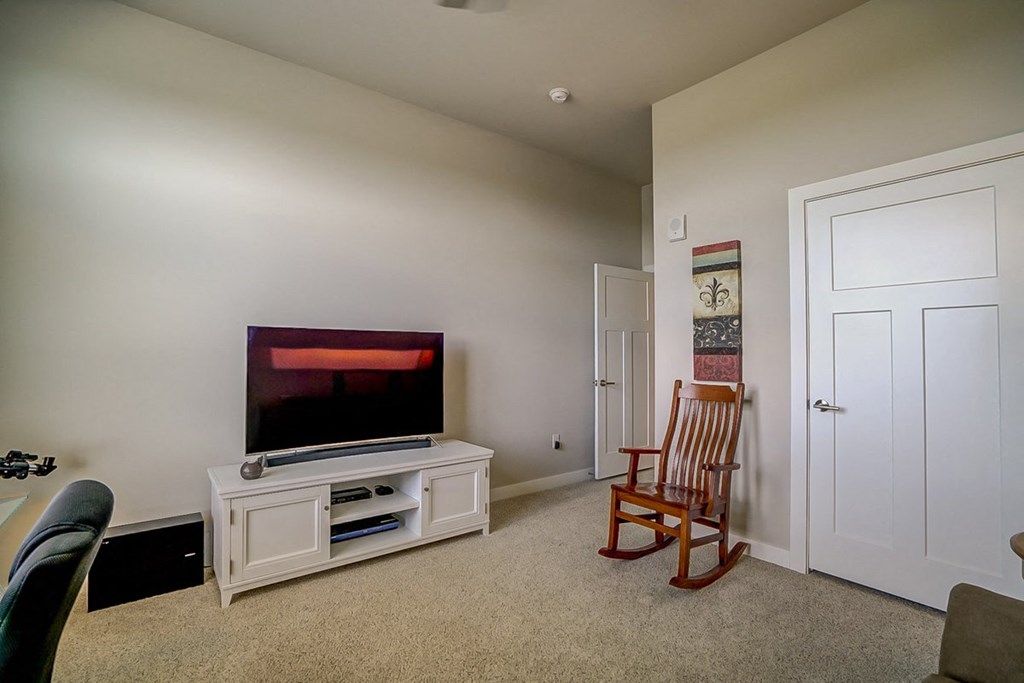 a living room with a tv and a rocking chair