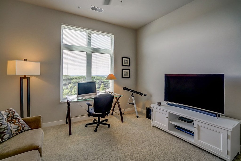 a living room with a tv and a desk with a laptop