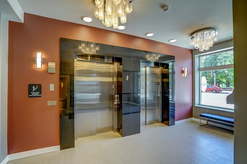 a lobby with two elevators and a window and a chandelier