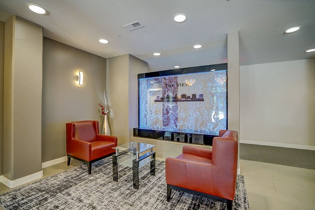 a lobby with two red chairs and a large screen tv