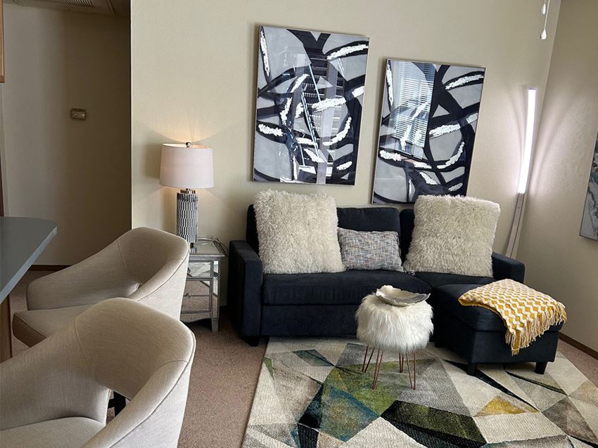 a living room with a black couch and two chairs and a rug