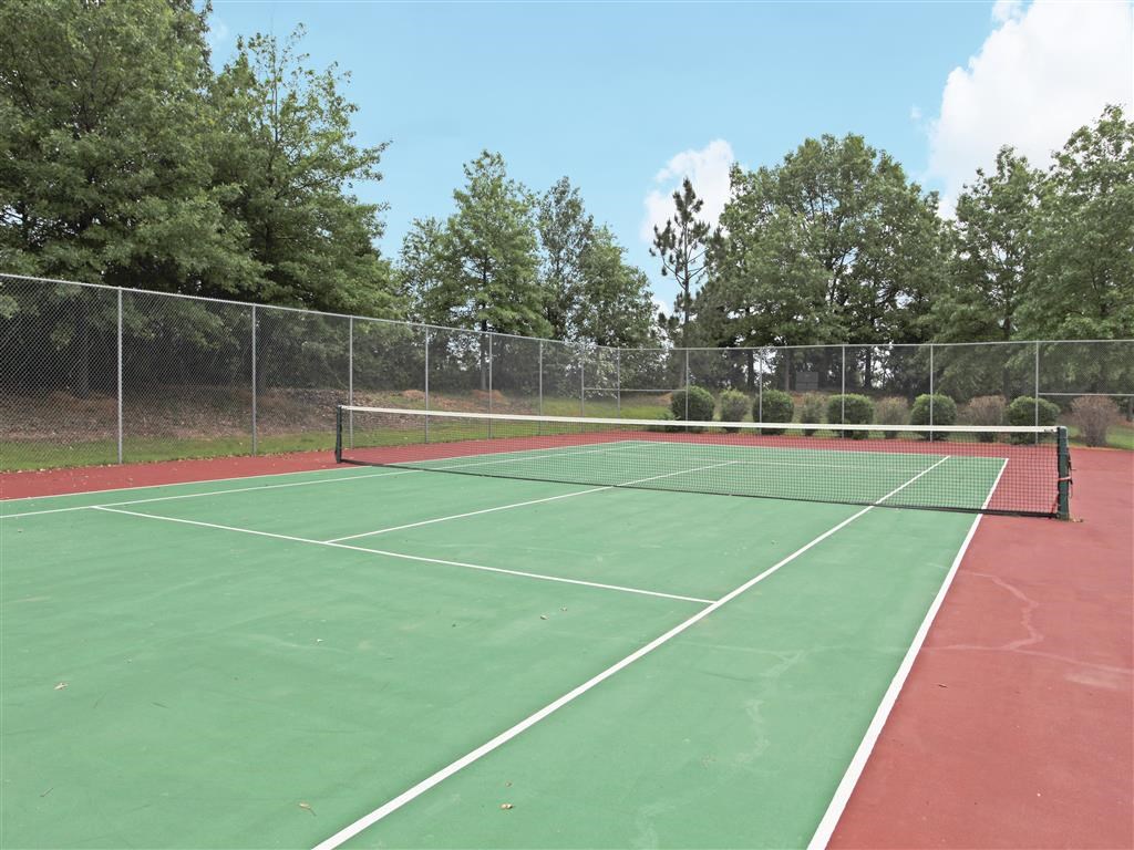 a tennis court with a fence and trees in the background