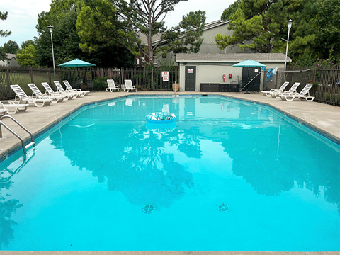 a large pool with white chairs and a fence around it