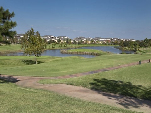 a golf course with a pond and houses in the background