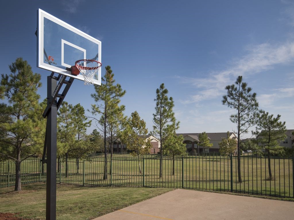 a basketball hoop in a park with a house in the background