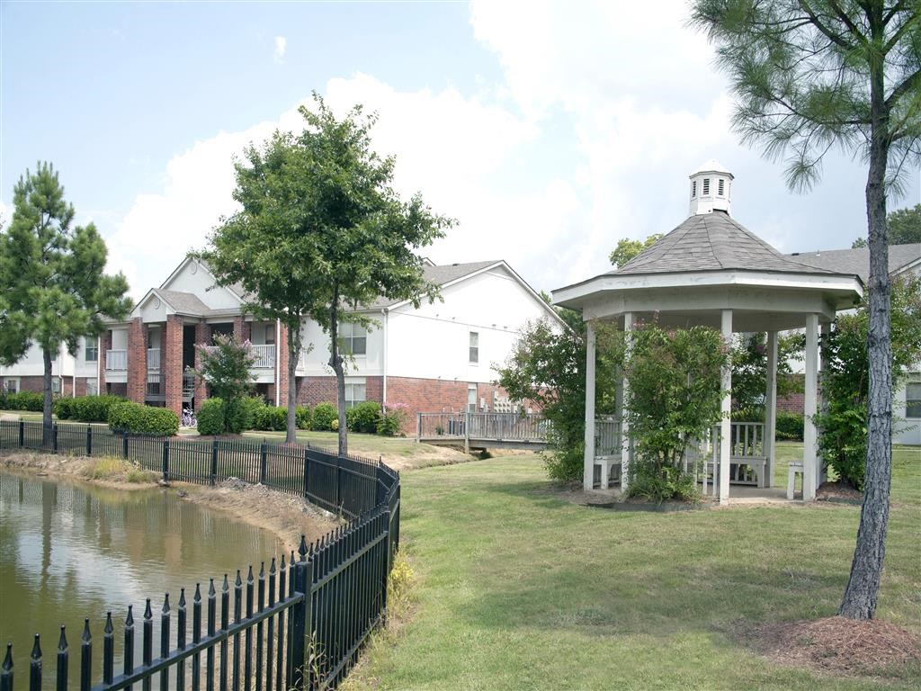 a gazebo and a pond in front of a building