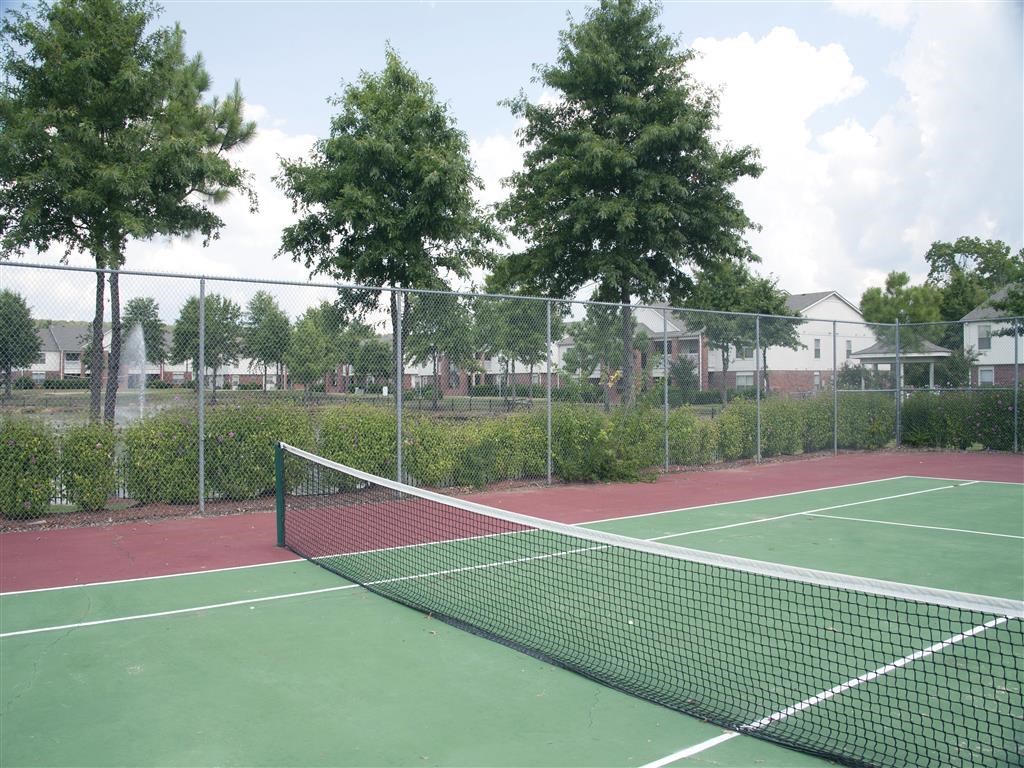 a tennis court with a fence and trees