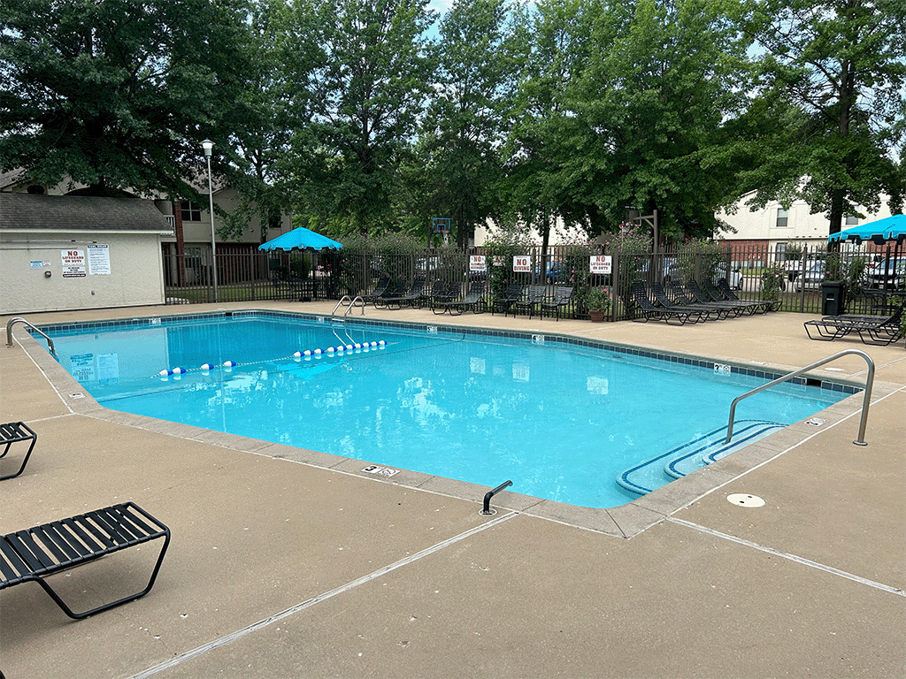 a resort style pool with chairs and umbrellas and trees