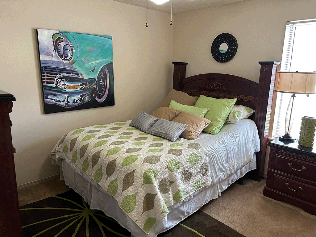 a bedroom with a bed and a painting of a car on the wall
