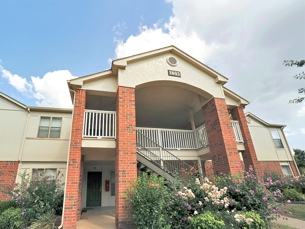 an apartment building with a balcony and flowering plants