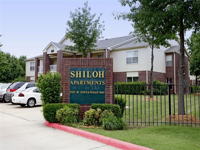 an apartment building with a sign in front of a fence