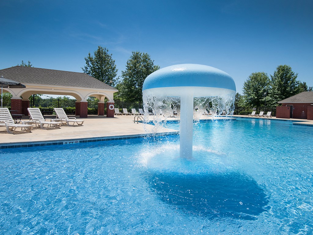 a water feature in the middle of a swimming pool with a fountain