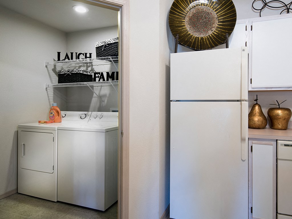 a kitchen with a white refrigerator and a washer and dryer and a sink