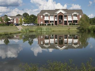 a house is reflected in the water in a pond