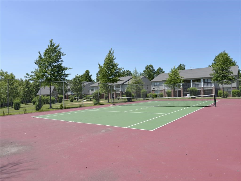a tennis court with apartments in the background