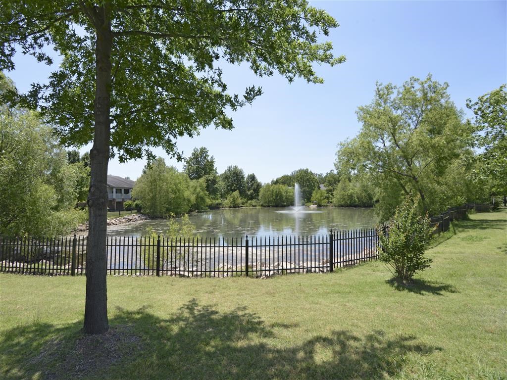 a pond with a fountain in the middle of a park
