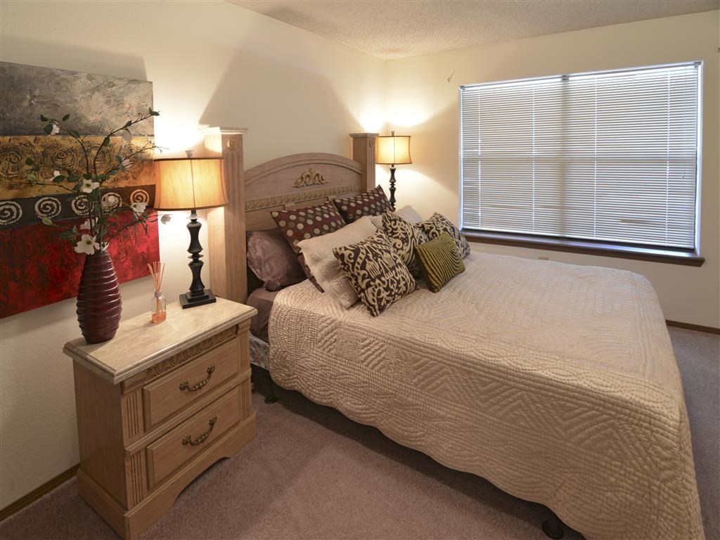 a bedroom with a bed and a dresser with lamps