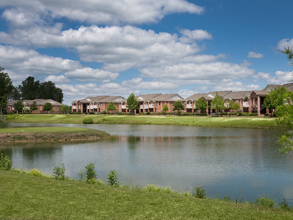 a pond in front of a row of apartments near a lake