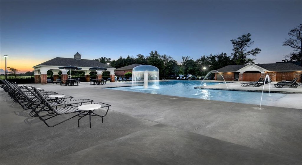 a swimming pool with chairs around it at night