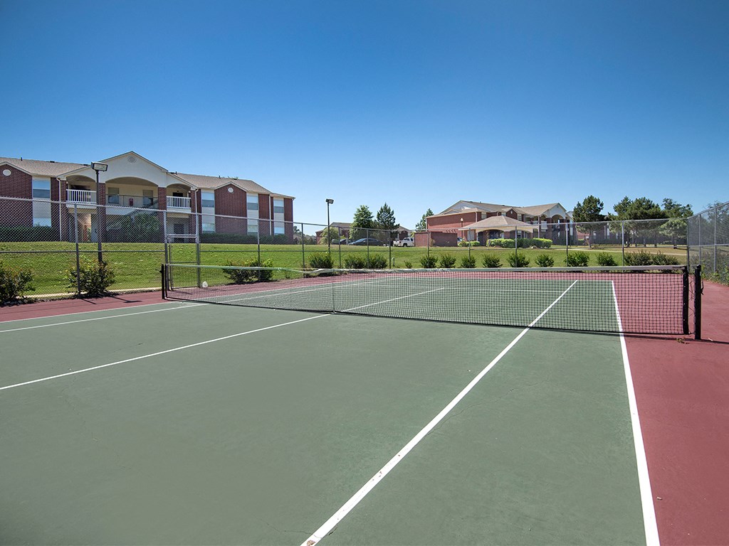 a tennis court with apartments in the background
