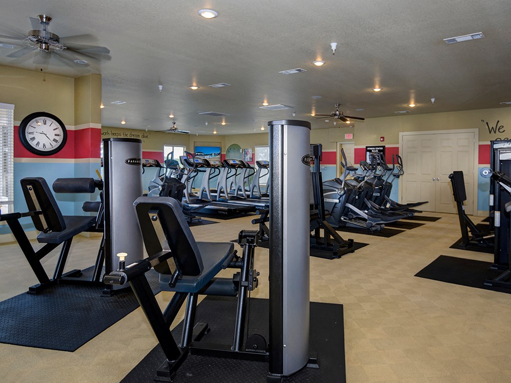 a gym with a lot of exercise equipment and a clock on the wall