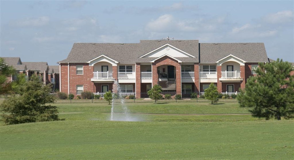 a fountain in the grass in front of a building
