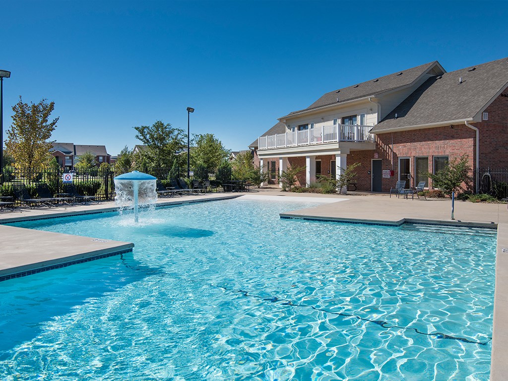 a swimming pool with a fountain in front of a house