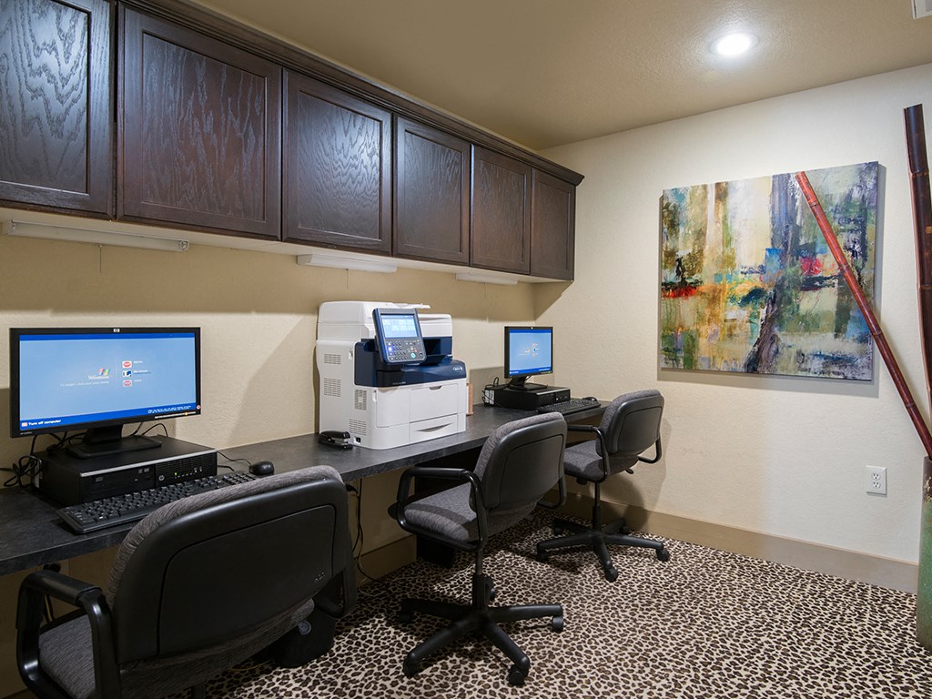 a business center with computers and chairs and a painting on the wall