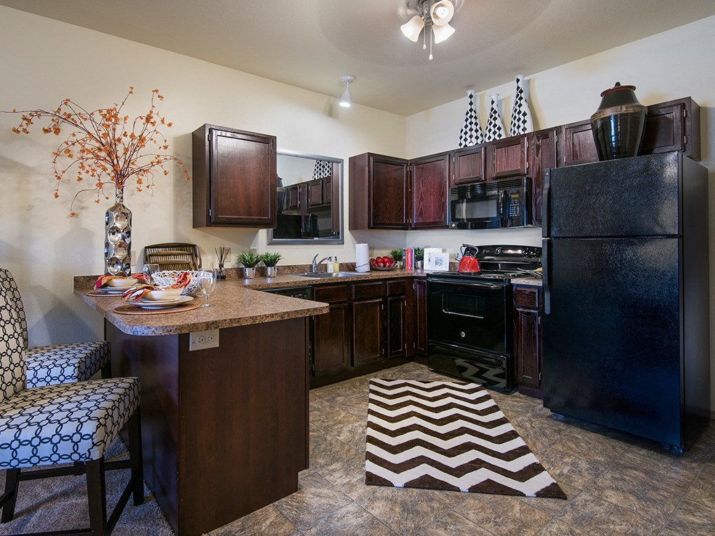 a kitchen with a center island and a black refrigerator