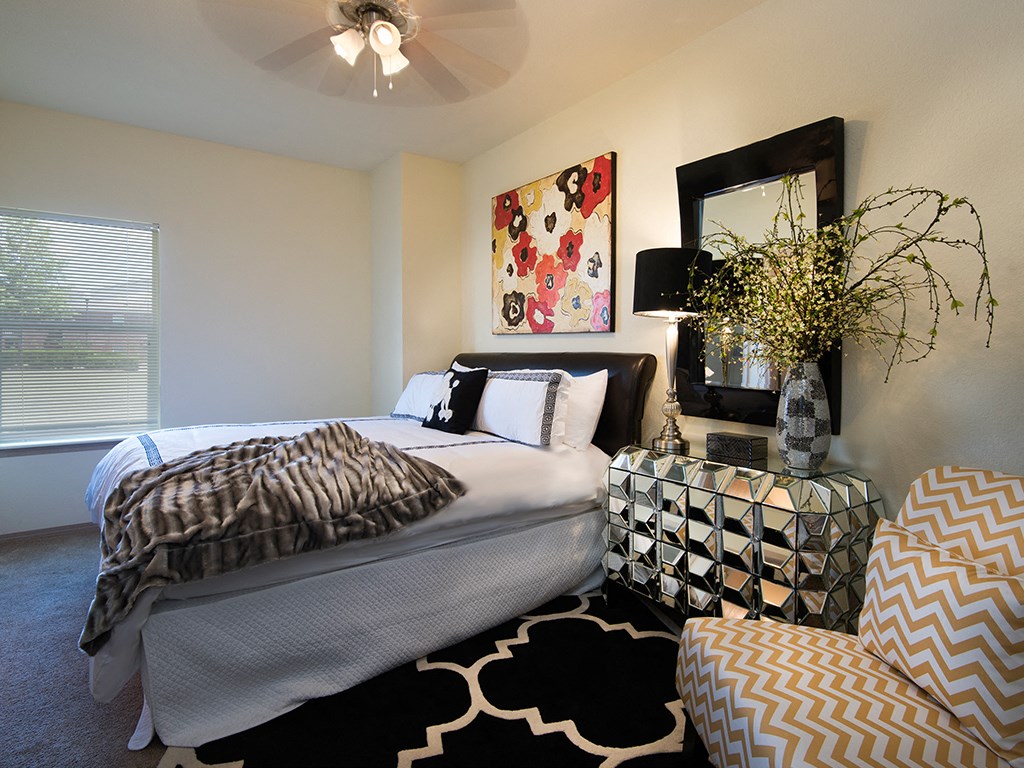 a bedroom with a bed and a chair and a mirror