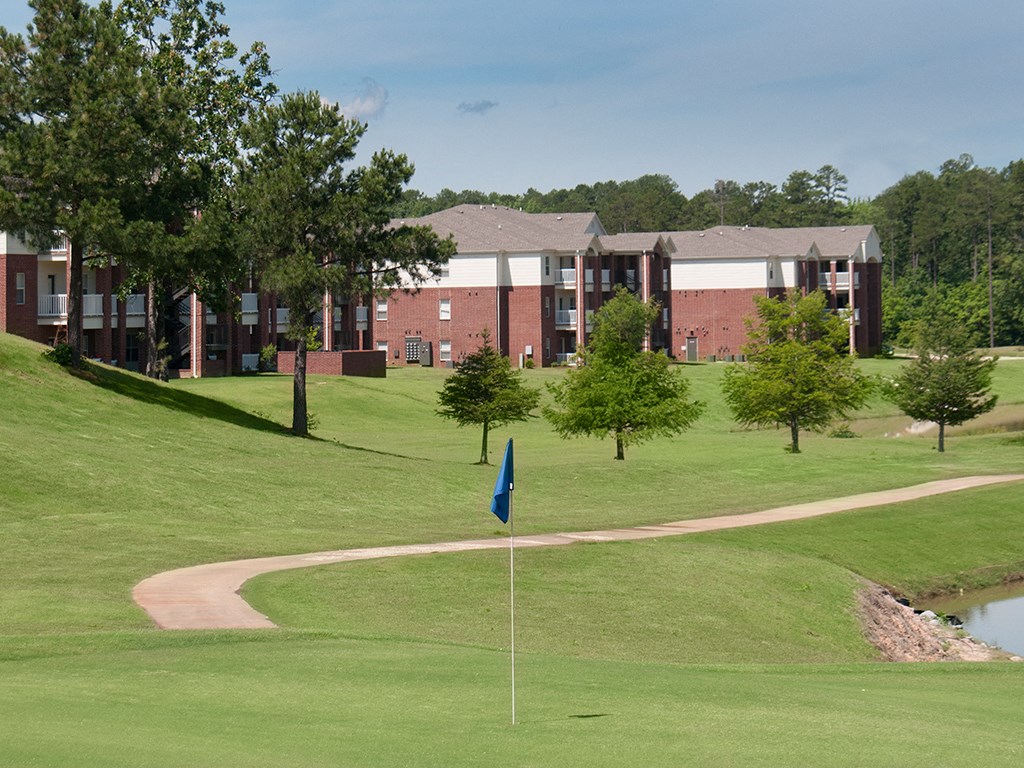 a golf course with a blue flag in front of an apartment building